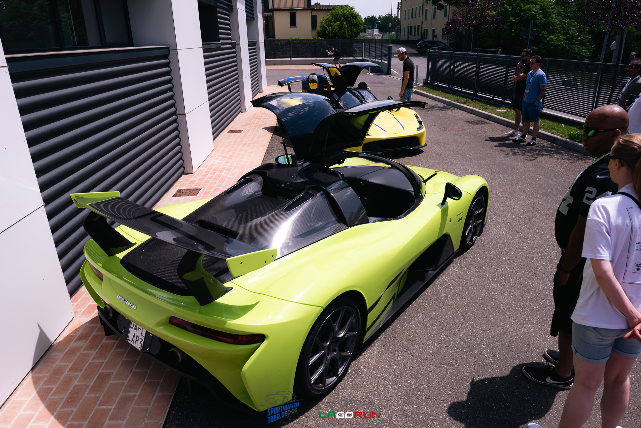 LagoRun participants beside green and yellow sports cars outside a building